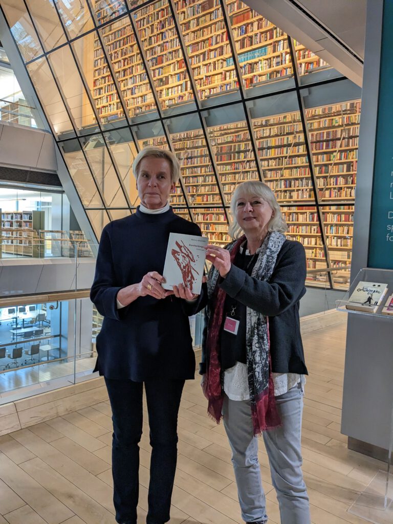 Barbara Miklaw vom Mirabilis Verlag überreichte Bibliotheks-Mitarbeiterin Anna Muhka ein Exemplar von "Brandmeldungen" von Martina Altschäfer.